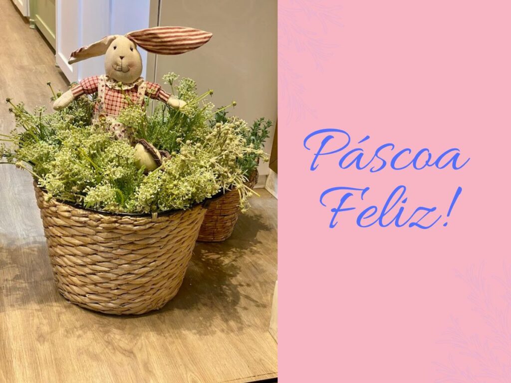 Cesto de palha com arranjo de flores brancas e coelho de pano artesanal com estampa xadrez. Imagem contém o texto "Páscoa Feliz!".